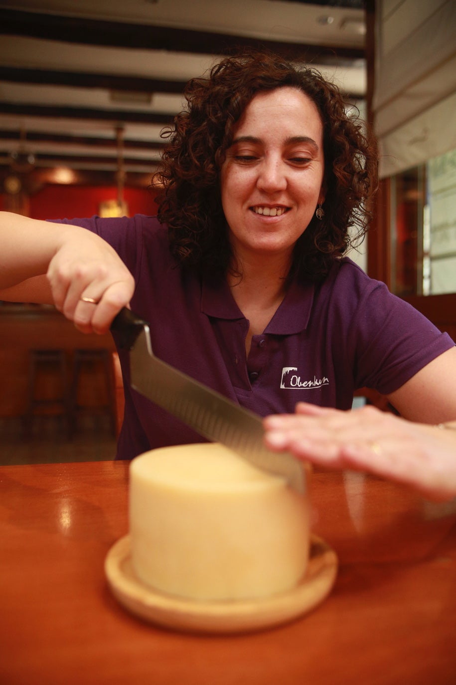 Su hija Estibaliz parte un queso Harana elaborado por la familia.