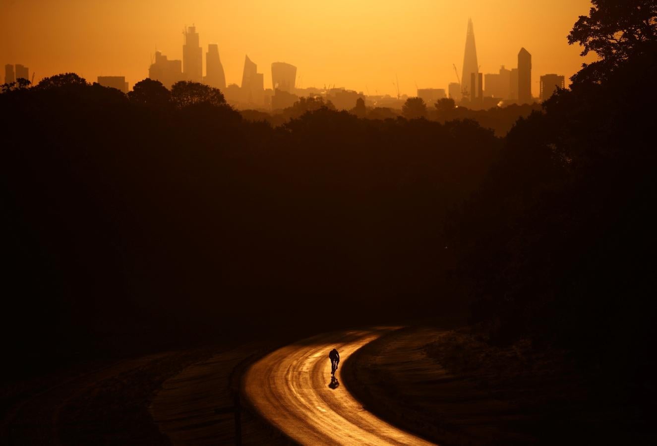 El sol se levanta tras el rascacielos The Shard y el distrito financiero mientras un ciclista recorre Richmond Park en Londres, Gran Bretaña.