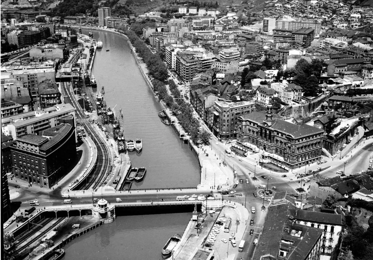 Año 1967, vista aérea del Ayuntamiento de Bilbao, campo Volantín, y la con barcos atracados ante el edificio Aznar
