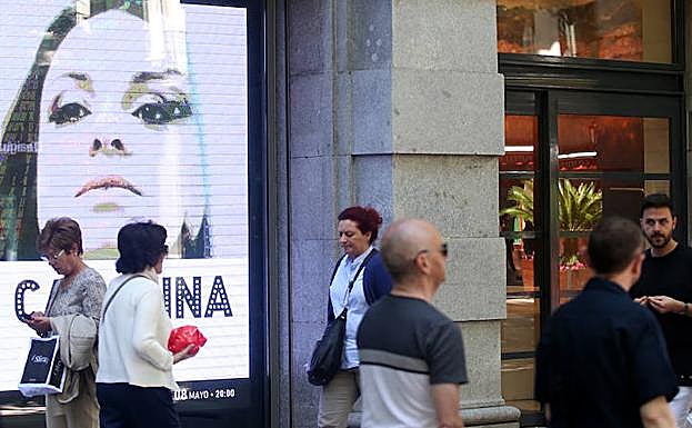 Paseantes junto al letrero luminoso de la Sala BBK.