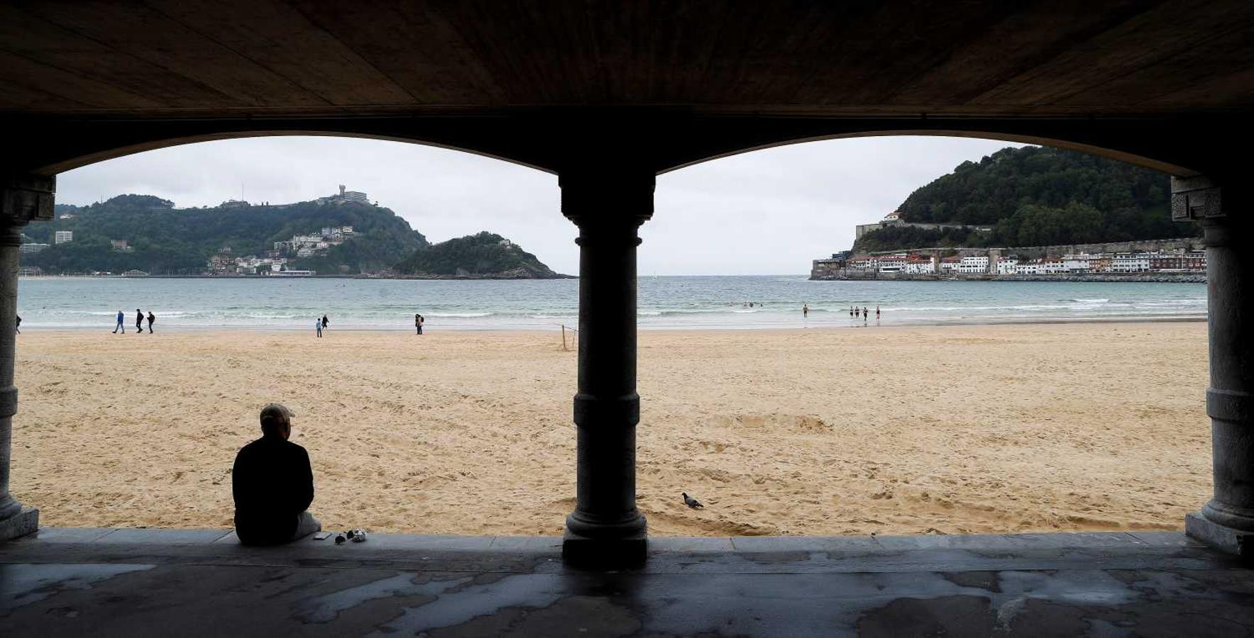 Un hombre observa la playa de La Concha de San Sebastián, en un día nublado