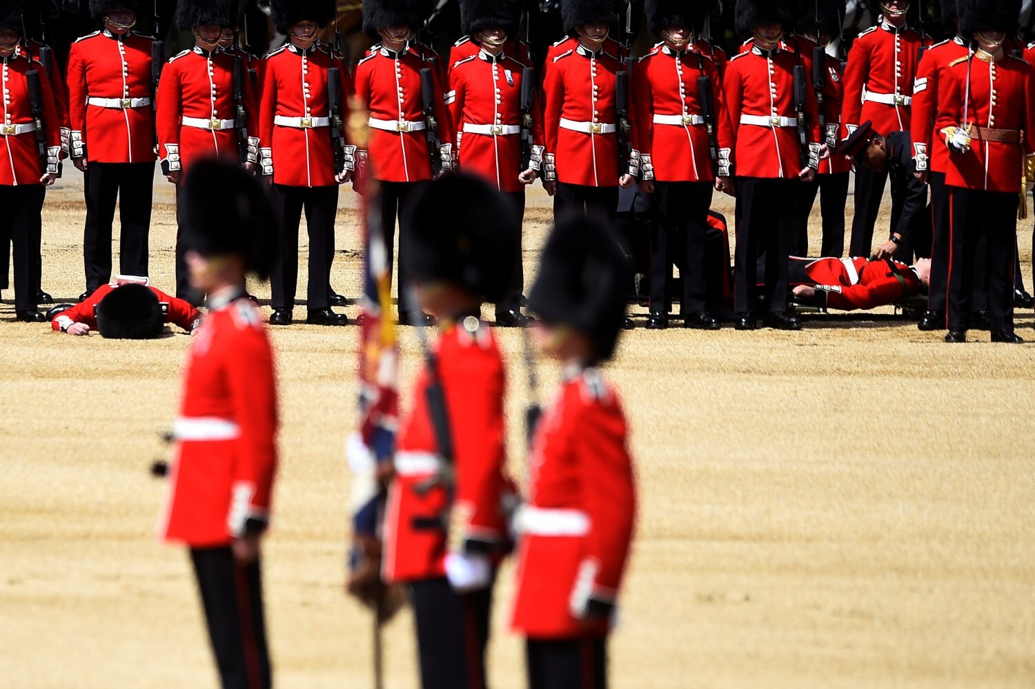 Guardias desmayados mientras sus compañeros siguen impasibles durante un ensayo antes del desfile de cumpleaños de la Reina la próxima semana, en Londres, Gran Bretaña, 