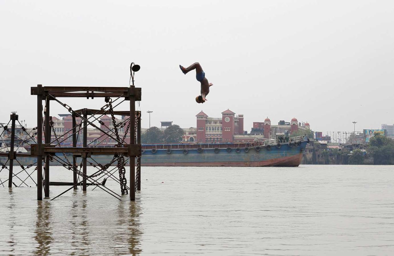 Un niño se lanza al río Ganges para refrescarse en un caluroso día de verano en Calcuta