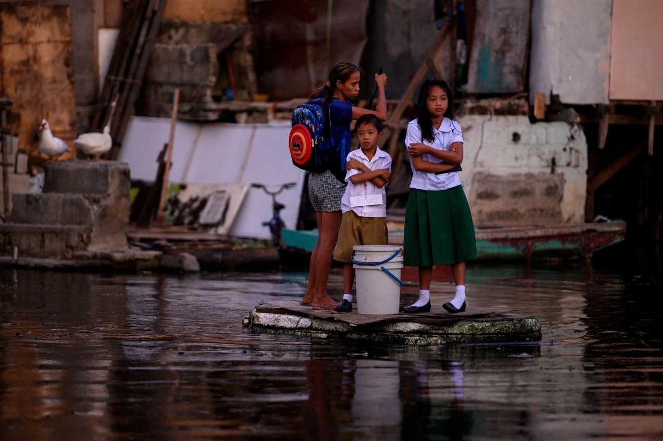 Estudiantes de primaria, que viven en Artex, inundado, viajan en un bote improvisado para asistir al primer día de clases en la Escuela Primaria en Malabon, al norte de Manila