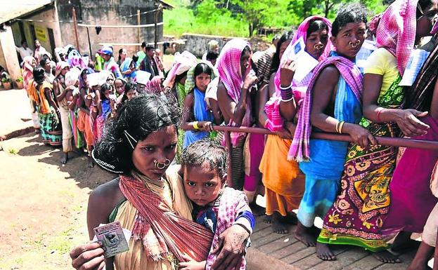 Mujeres de piel oscura aguardan para votar en Odisha (In dia). 