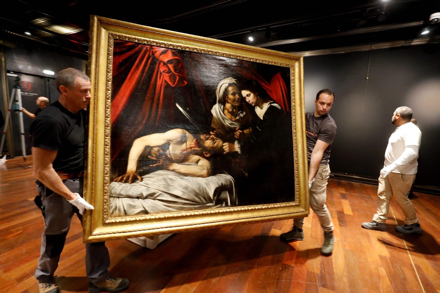 Trabajadores llevan la pintura que algunos expertos creen que es "Judith Beheading Holofernes" de Caravaggio para su presentación pública en la casa de subastas Drouot en París.