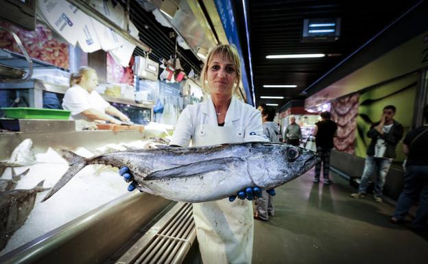 La pescadera Juli Torres muestra uno de los bonitos del Norte 'pioneros' que han llegado este miércoles al mercado de la Ribera