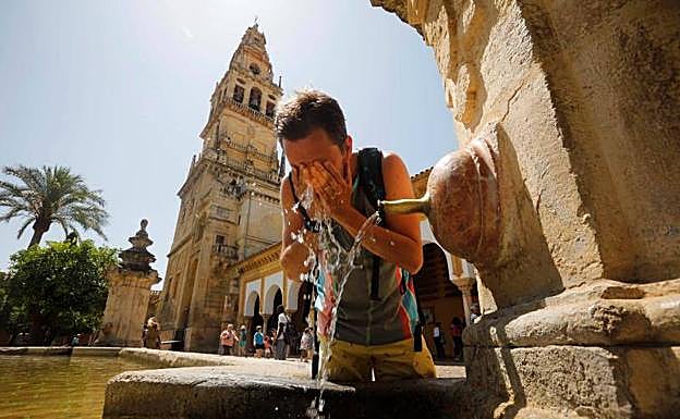 Un turista se refresca en una de las fuentes del patio de los Naranjos de la Mezquita-Catedral de Córdoba.