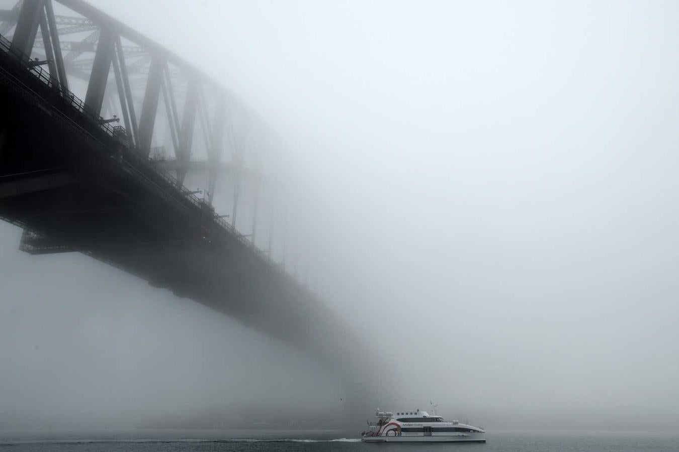 Un barco pasa bajo el puente del puerto de Sídney (Australia)