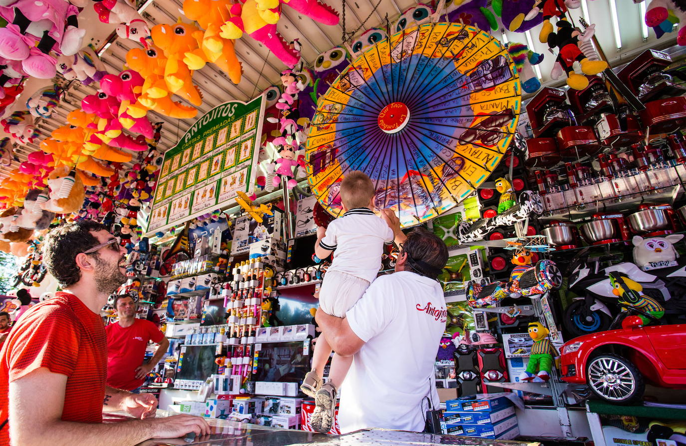 Unos asistentes a las barracas reciben un premio de la tómbola