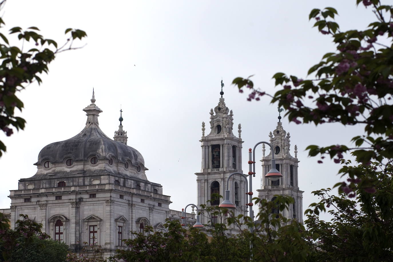 Palacio de Mafra. Con esta construcción, Portugal puede presumir de contar con dos nuevos sitios en la lista de nuevas maravillas de la Unesco. Este palacio se sitúa a 30 kilómetros al noroeste de Lisboa y fue proyectado por el rey Juan V en 1711 para plasmar su concepción de la monarquía y el Estado. El edificio hizo el papel de palacio real, capilla regia, monasterio franciscano y biblioteca, que en la actualidad atesora unos 36.000 libros.