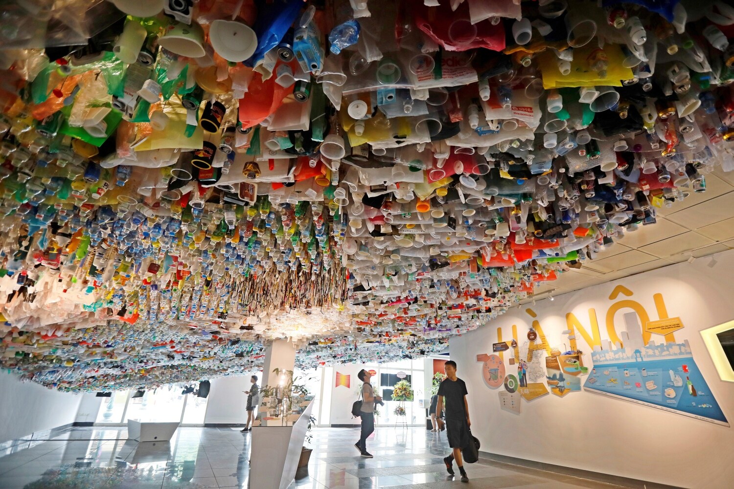 Varios personas recorren la exposición "Reduce la basura" en el Centro Cultural Francés de Hanoi (Vietnam). La muestra reúne piezas creadas con objetos desechables de plástico.