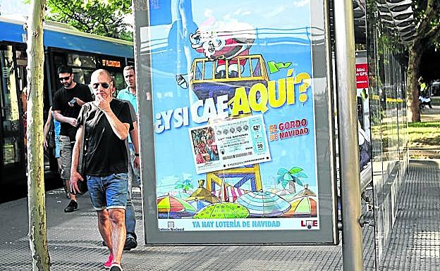 Cartel que anuncia el sorteo de Lotería de Navidad expuesto en una marquesina de autobús en pleno mes de julio. 