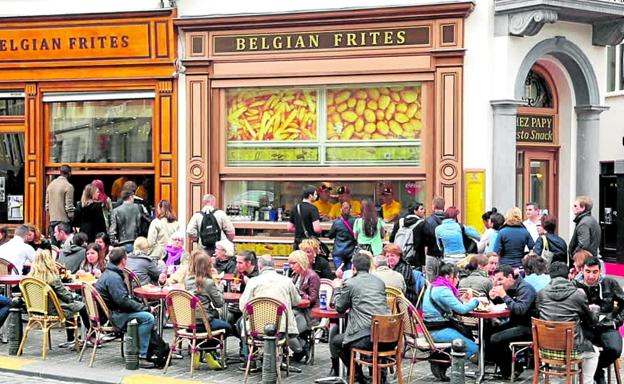 Clientes degustan 'frites' en la terraza de un establecimiento especializado de Bruselas. 