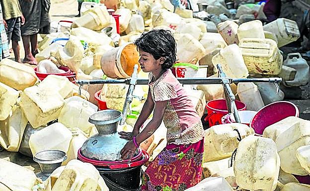 Una niña recoge agua para abastecer a su familia.
