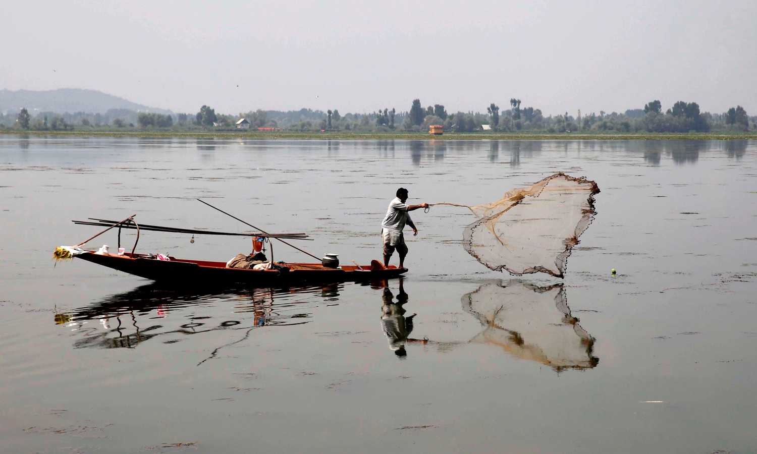Un hombre pesca en el Lago Dal de Srinagar, en Cachemira