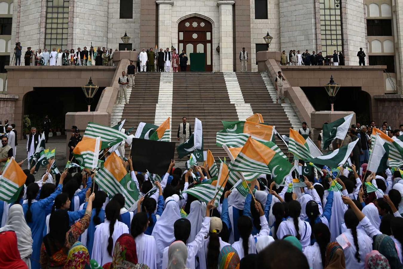 La gente agita las banderas nacionales de Pakistán y de Cachemira por la llegada del primer ministro Imran Khan