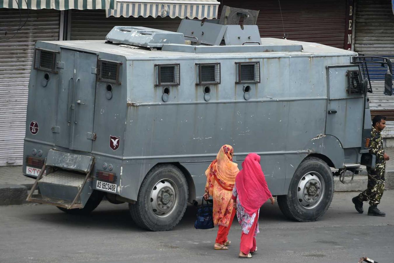 Residentes indios de Cachemira pasan junto a un vehículo blindado paramilitar en Srinagar