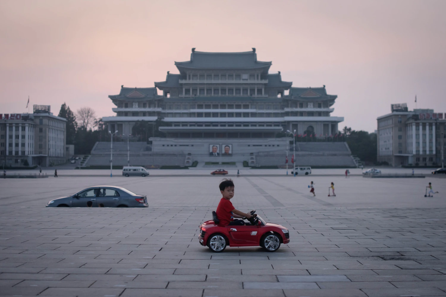 Un niño conduce un automóvil de juguete eléctrico en miniatura a través de la plaza Kim Il Sung en Pyongyang. - Corea del Norte.