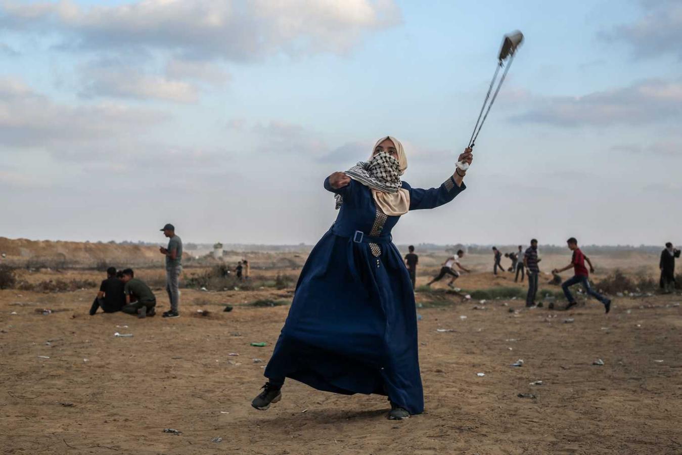 Una manifestante palestina dispara con su honda a soldados israelíes, al otro lado de la valla de alambre de espinas, en la frontera con Cisjordania, en Khan Yunis