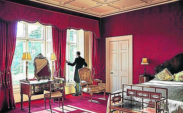 Un mayordomo abre las ventanas de una de las lujosas estancias del inmueble que regentan los condes de Carnarvon.