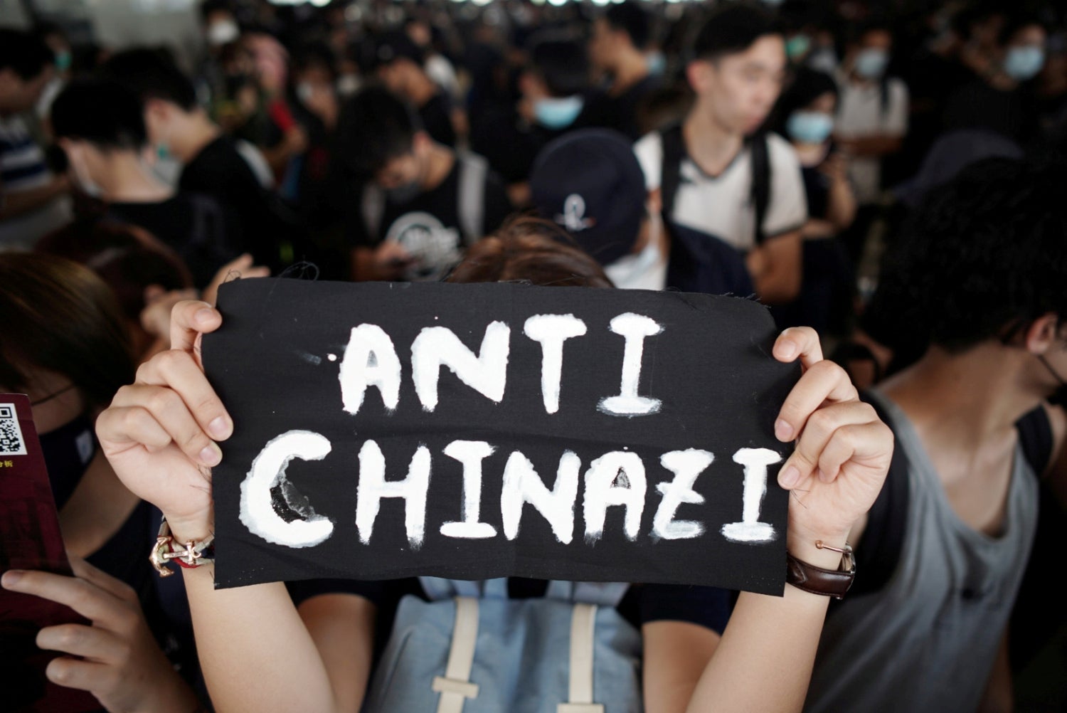 Una mujer muestra el mensaje “Anti Chinazi” mientras se reúne con otras personas en el Edificio de Tribunales Legales de West Kowloon para mostrar su apoyo a los 96 manifestantes antigubernamentales que fueron arrestados hace dos días en Hong Kong, China.