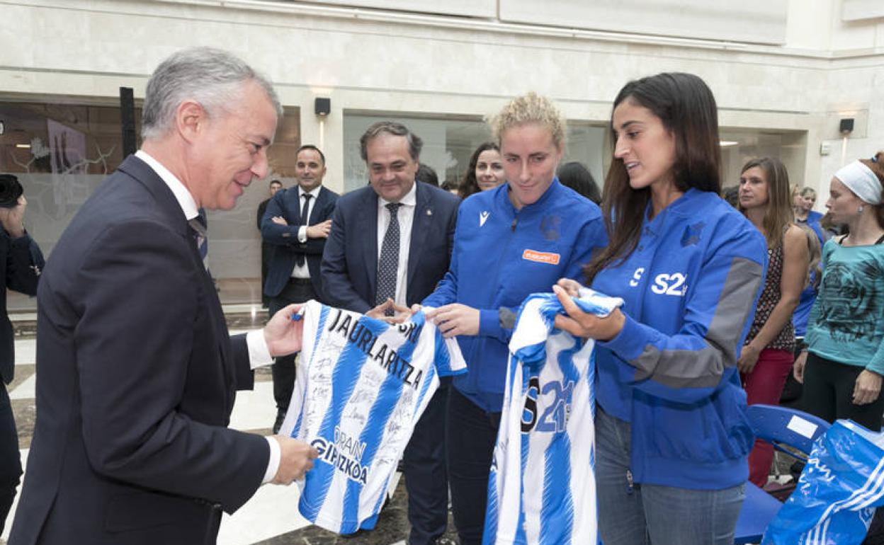 Urkullu recibiendo la camiseta de la Real Sociedad de fútbol y de hockey hierba. 