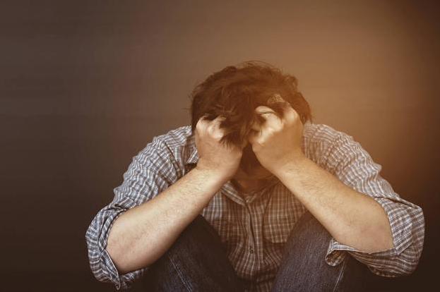 Un hombre en actitud triste, con el gesto común de llevarse las manos a la cabeza.