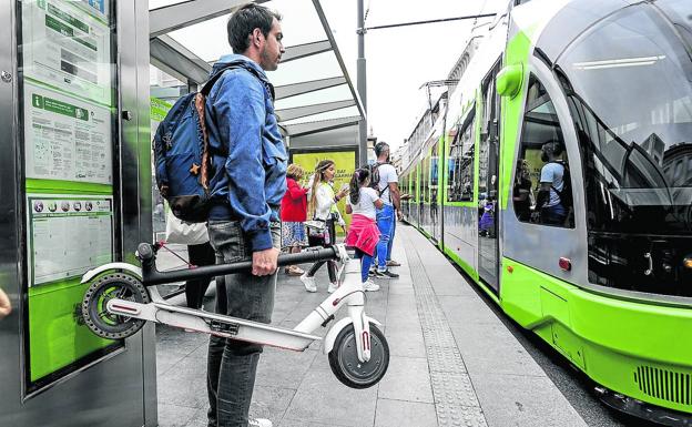 Un joven con un patinete plegado se dispone a tomar el tranvía en Vitoria. 