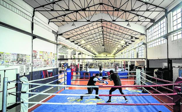 Los púgiles entrenan en el ring en un pabellón industrial. 