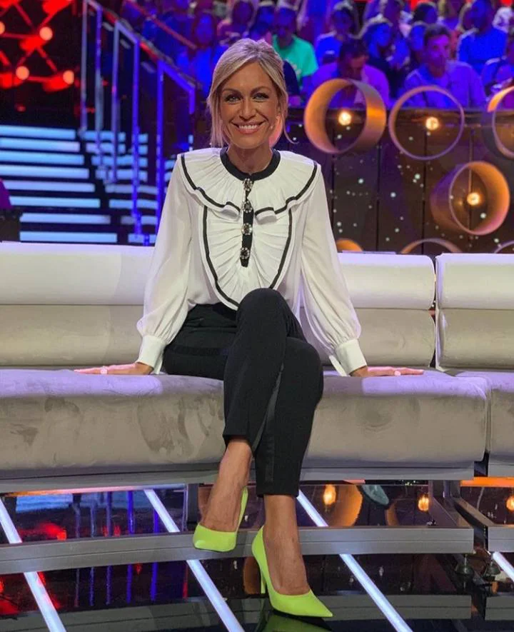 La presentadora Luján Argüelles lució esta blusa de estilo vintage con detalle de volantes y botones tipo joya, combinada con unos pantalones negros ajustados con banda lateral satinada y unos zapatos de tacón en verde flúor para rematar el look.