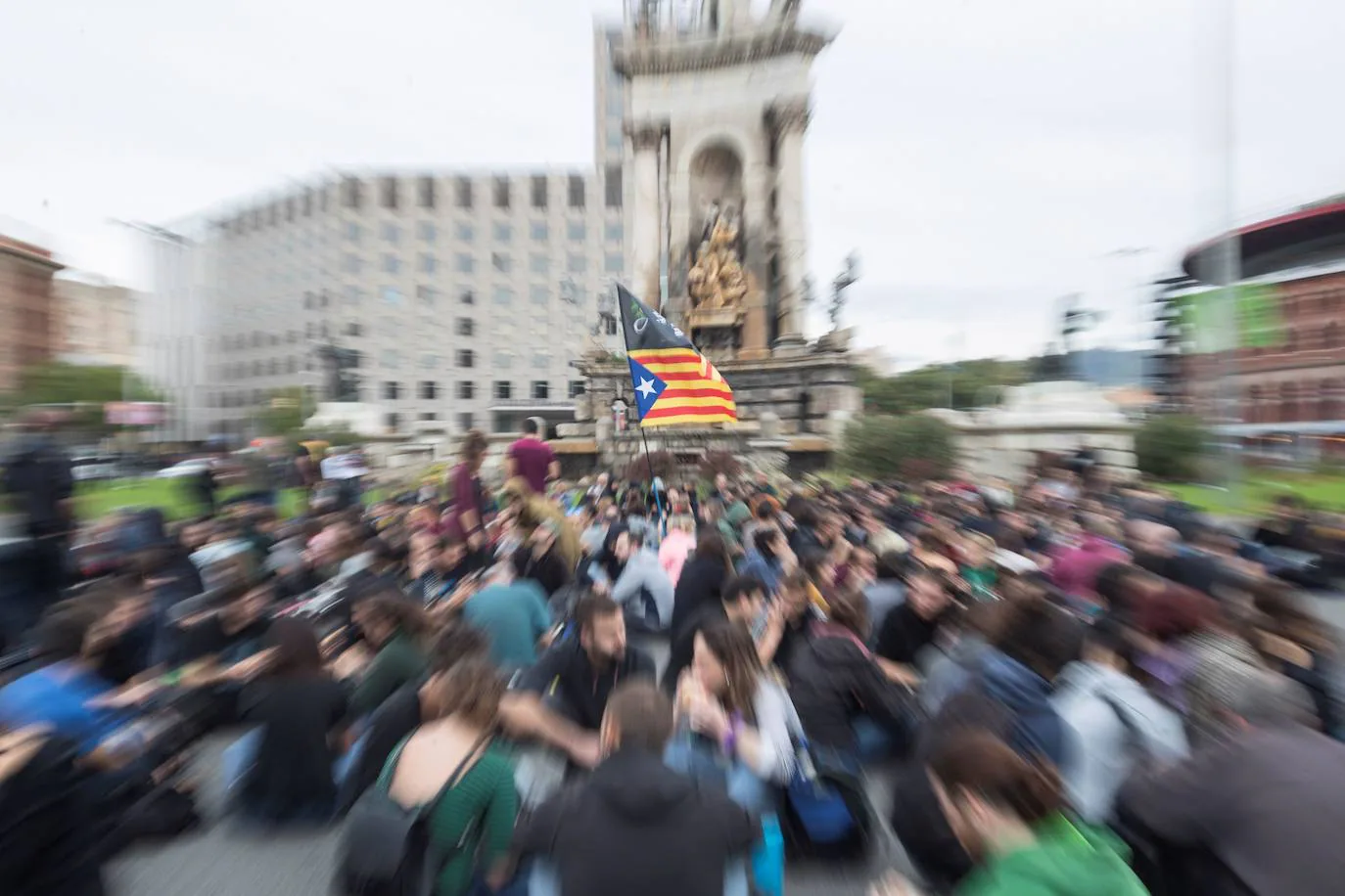 Un grupo de manifestantes realiza una sentada en la Plaza de España de Barcelona