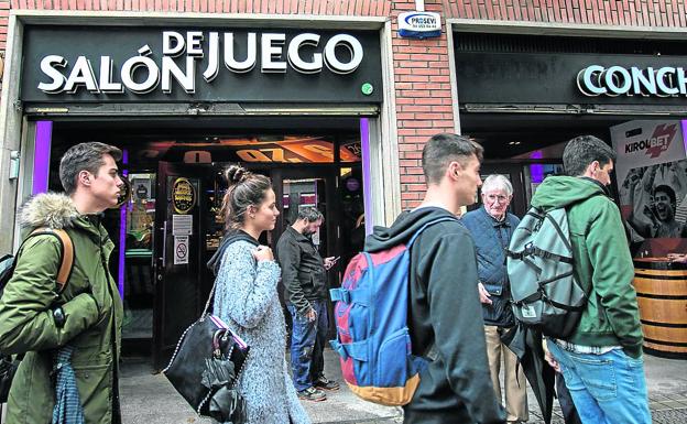 Varios jóvenes pasan por delante de un salón de juego situado en Bilbao.