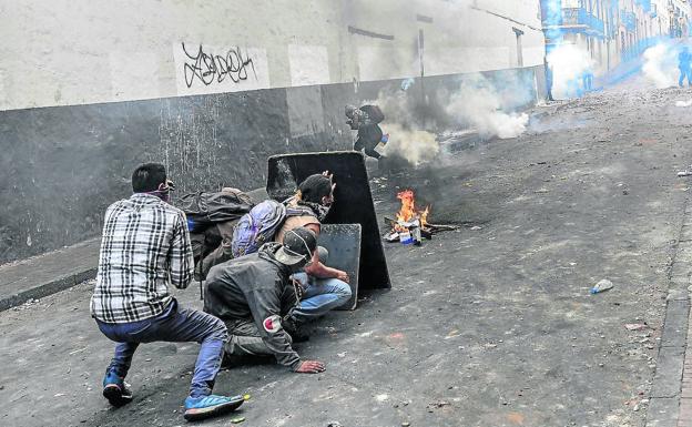 Imagen principal - Arriba: Ecuatorianos que protestan por la supresión de los subsidios a los combustibles se protegen en Quito de los gases lacrimógenos. Abajo, a la izquierda: Disturbios en las calles de Santiago de Chile. A la derecha: Una mujer se pinta en un barrio pobre de Buenos Aires. 