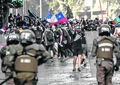 Imagen secundaria 1 - Arriba: Ecuatorianos que protestan por la supresión de los subsidios a los combustibles se protegen en Quito de los gases lacrimógenos. Abajo, a la izquierda: Disturbios en las calles de Santiago de Chile. A la derecha: Una mujer se pinta en un barrio pobre de Buenos Aires. 