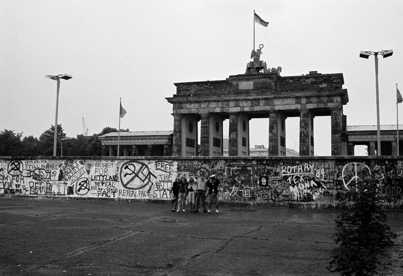 (7) Antes: Turistas posan frente al Muro de Berlín en la Puerta de Brandenburgo, el 6 de junio de 1989.
