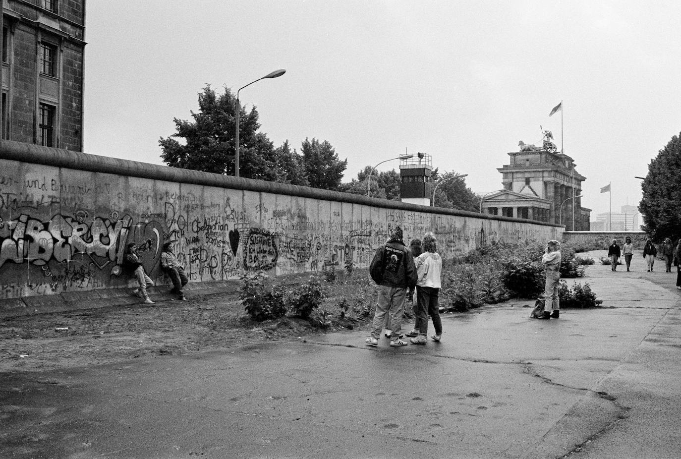 (6) Antes: Gente posando en el Muro de Berlín junto a la Puerta de Brandenburgo.