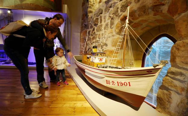 Una familia examina la maqueta de un pesquero en el museo de Bermeo. 