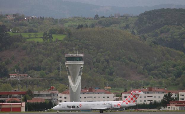 Un avión de Volotea se prepara para despegar, con la torre de control de Loiu de fondo. 