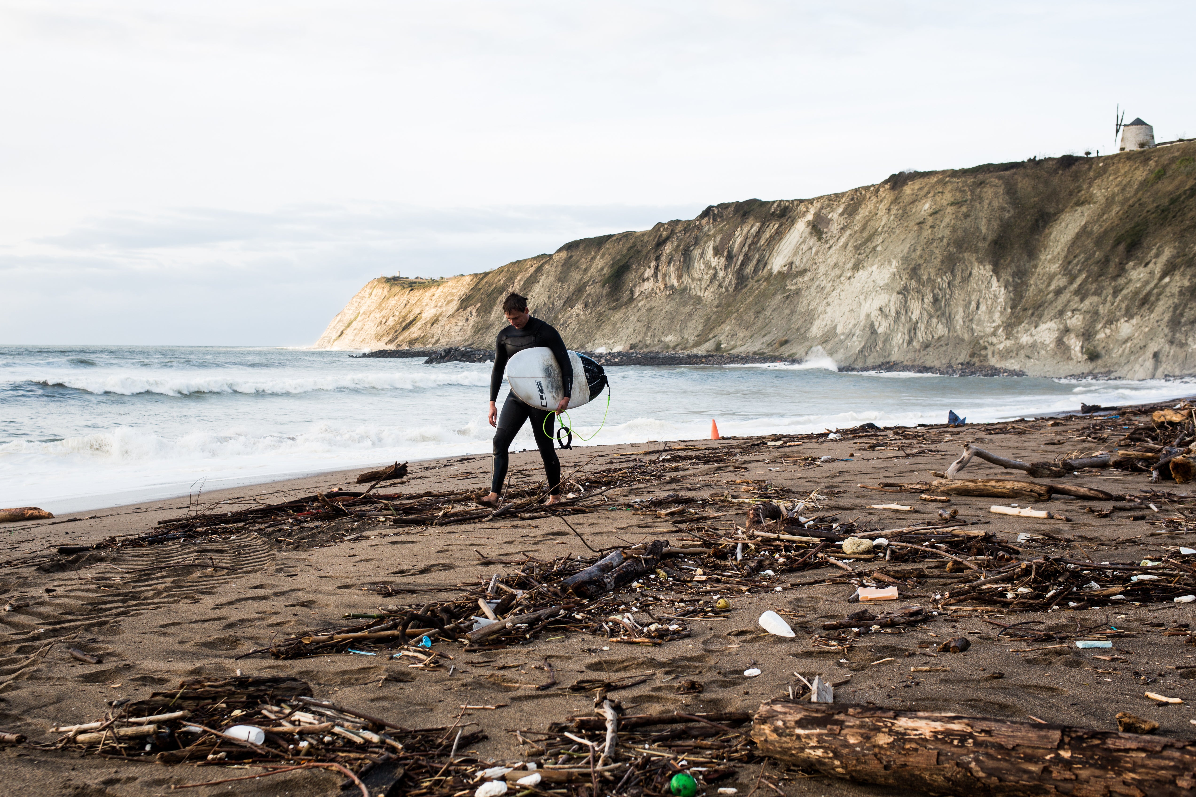 El temporal que azota estos días las costas vizcaínas está provocando que el mar arrastre todo tipo de suciedad a las playas: palos, algas, plásticos... En la imagen un surfista pasea en la playa de Arrigunaga (Getxo)