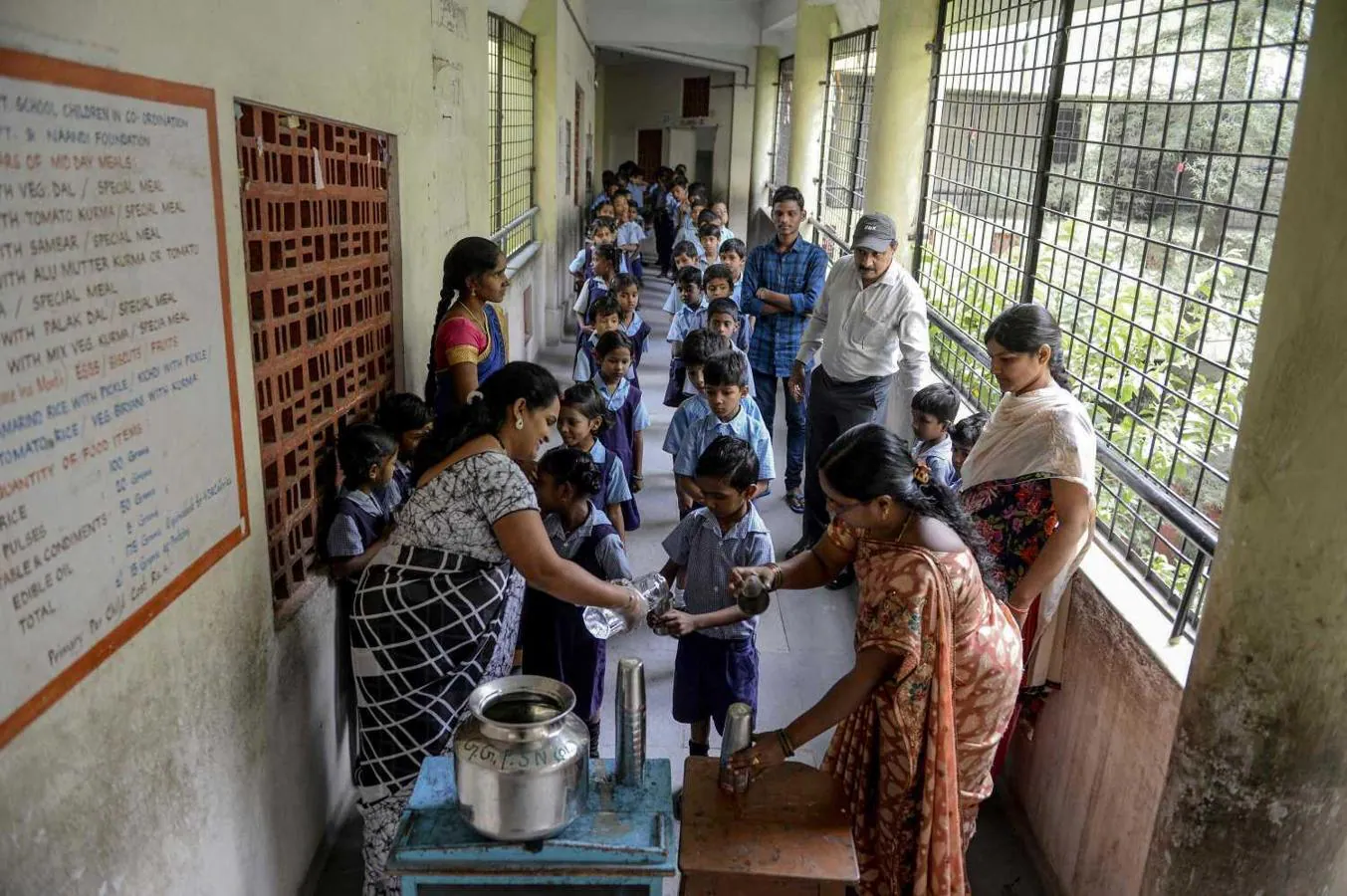 Las maestras dan agua potable a los niños tras el lanzamiento del programa "Water Bell" del gobierno de Telangana, India, para garantizar que los niños beban suficiente agua