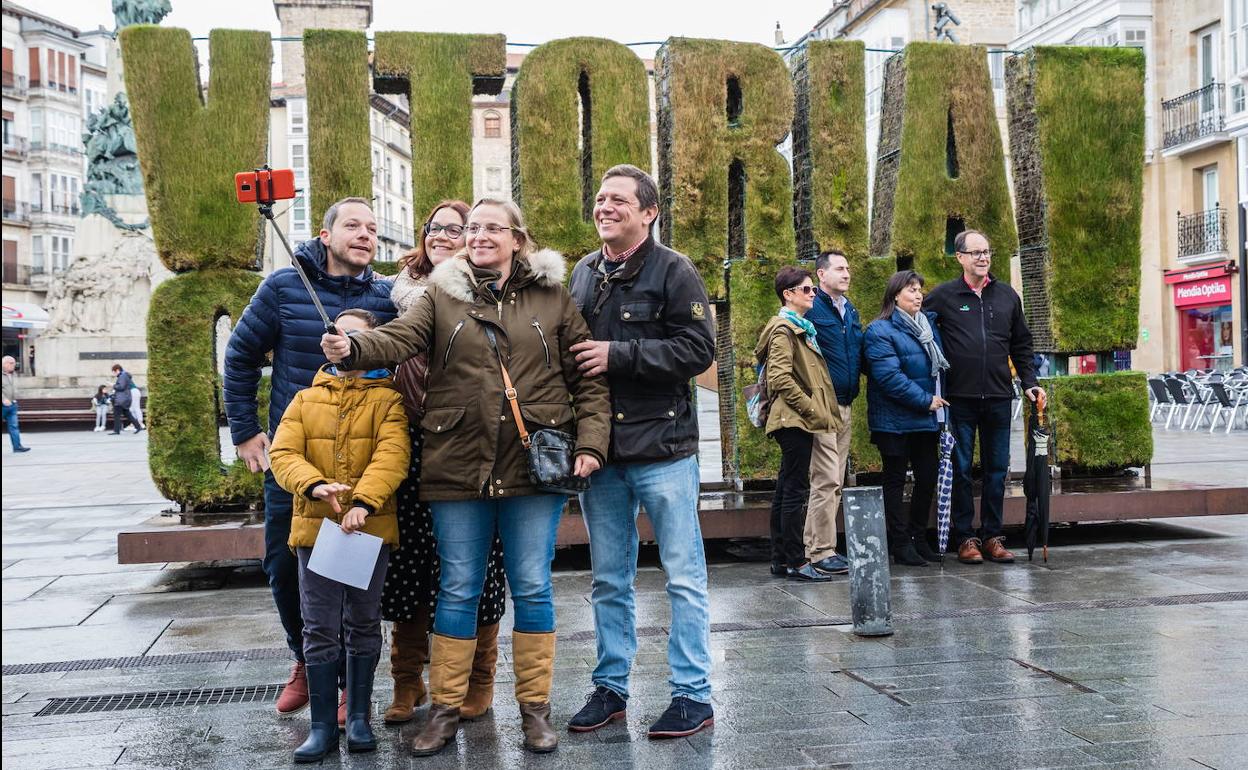 Un grupo de turistas se fotografía junto a la escultura vegetal de la plaza de la Virgen Blanca. 