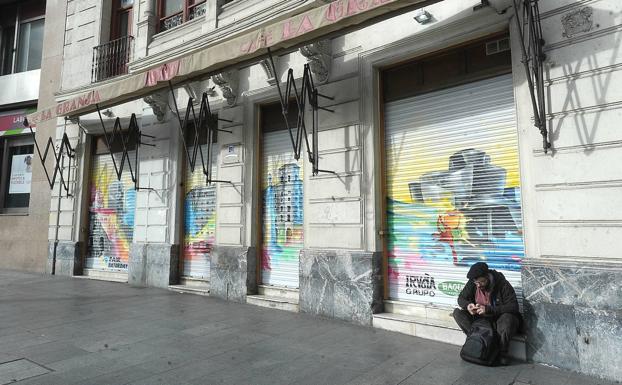 Un hombre sentado en la entrada del antiguo café.