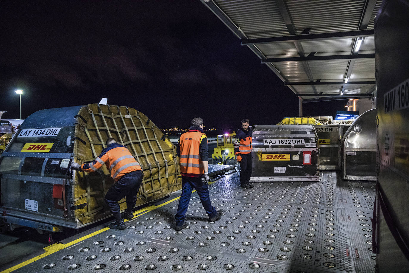 Operarios trasladan los contenedores que llegan en los aviones a las instalaciones cargueras de la empresa.