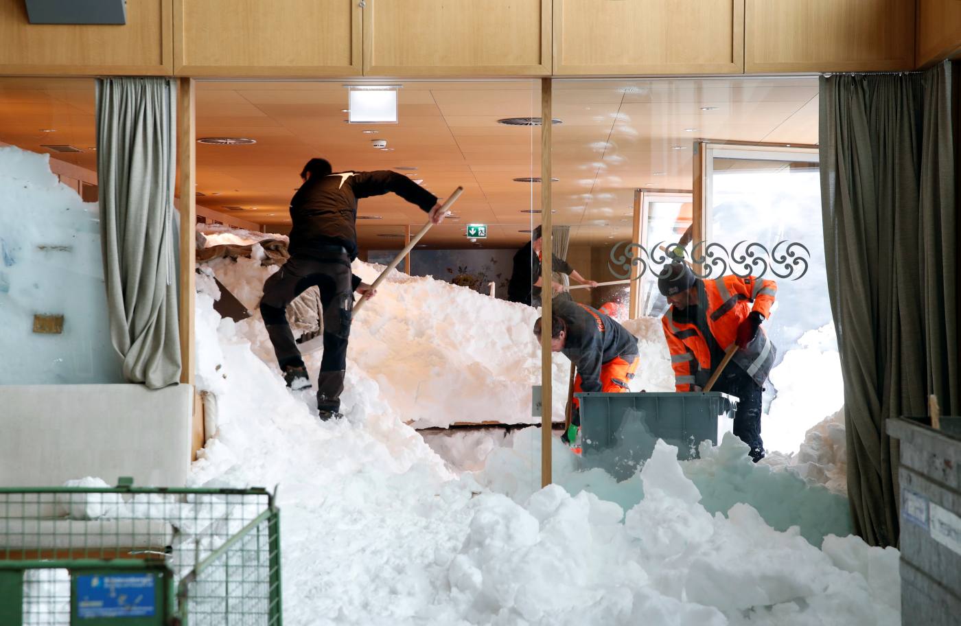 Trabajadores retiran nieve a paladas de un restaurante después de una avalancha en un resort de montaña de Santis-Schwaegalp, en Suiza.