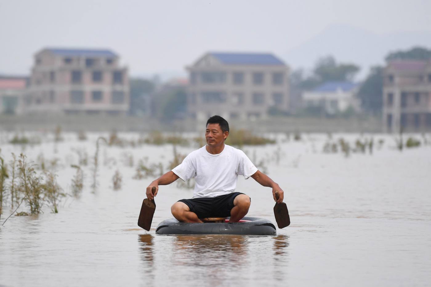 Tras una increíble crecida, un lugareño se traslada remando sobre un neumático en el pueblo de Longtou, en la provincia china de Hunan.