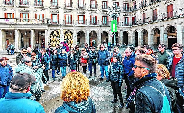 Un grupo de turistas atiende las explicaciones de un guía en la plaza de España.