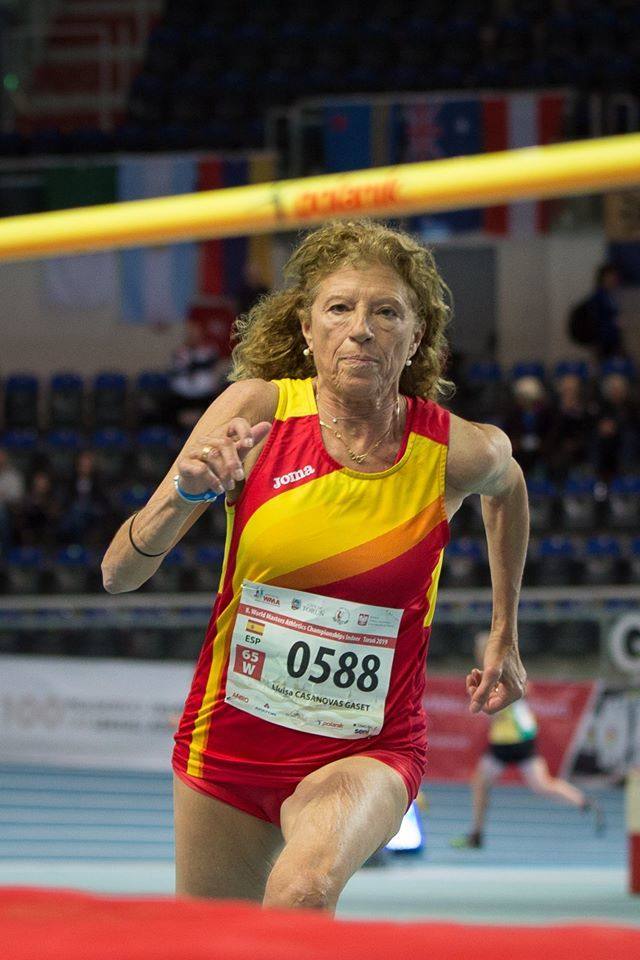 Lluïsa Casanovas Gaset, 67 años. A fuerza de acompañar a sus hijas a sus propios entrenamientos de atletismo, acabó por integrar un grupo de apoyo formado por los padres que también participaba en los mismos. A sus 67 años, Lluïsa Casanovas es miembro vocal de la Comisión Máster de la RFEA y, más importante aún, campeona de España, europea y mundial en diversas pruebas de saltos y sprint en varias categorías correlativas de atletas veteranas. Por citar sus logros sólo en categoría W65, Lluïsa Casanovas es campeona mundial bajo techo este mismo año en la ciudad polaca de Torun en la modalidad de salto de altura (1,21 m), mundial al aire libre de 2018 en Málaga (1,24 m), europea de 2017 en triple salto al aire libre (7,74 m) en la localidad danesa de Aarhus y, por supuesto, tetracampeona de España en Sagunto el pasado mes de junio en 100 m (17:35 con viento en contra), altura (1,20 m), longitud (3,35 m) y triple salto (7,88 m). Sin duda alguna, una de las atletas máster más destacadas de España. 