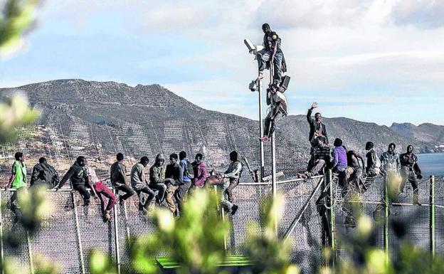 Subsaharianos en lo alto de la valla de Melilla.