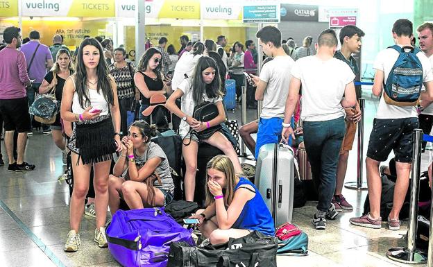 Pasajeros ajenos a la información hacen cola en los mostradores de Vueling en El Prat. 